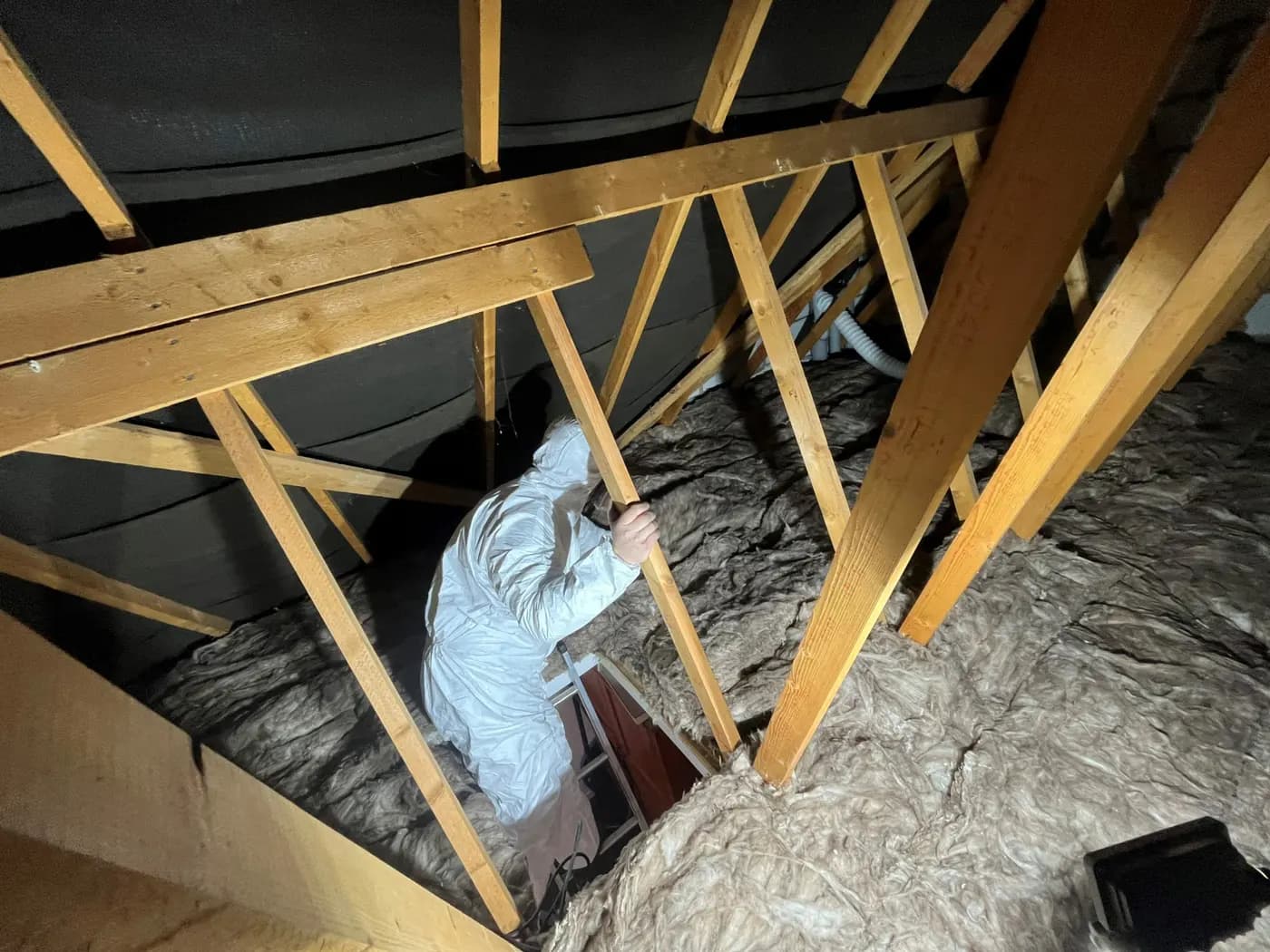 An installer laying loft insulation between the joists